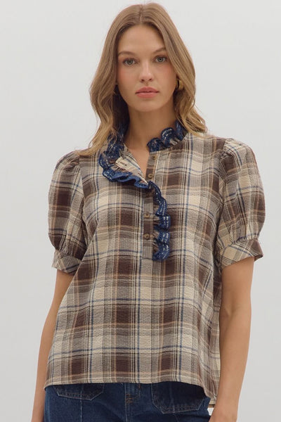 Woman wearing a plaid shirt with ruffled details and blue jeans on a white background