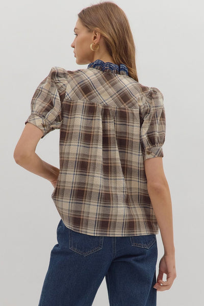 Person wearing a plaid shirt and blue jeans on a plain background