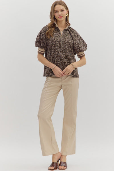 Woman wearing a patterned blouse and beige pants on a white background