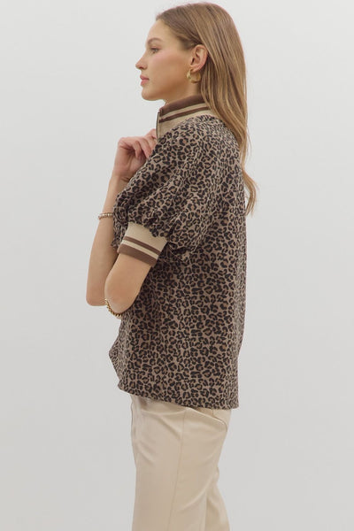 Woman wearing a leopard print shirt with beige accents on a plain background