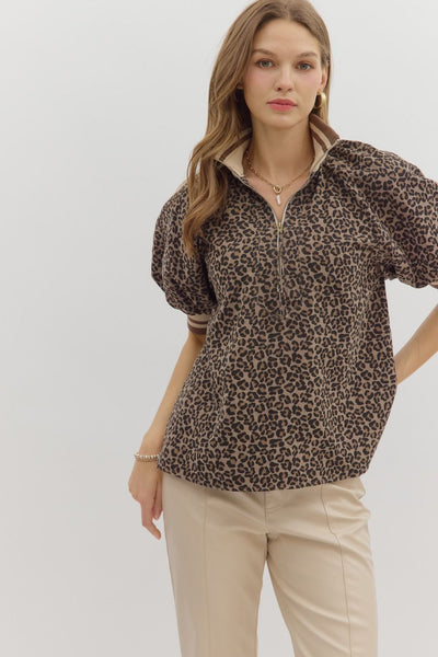 Woman wearing a leopard print blouse and beige pants on a light gray background