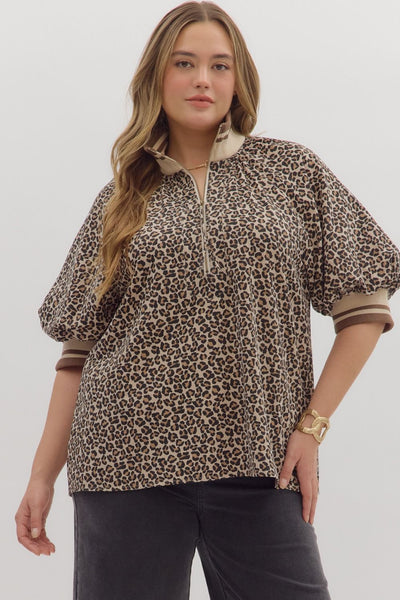 Woman wearing a leopard print blouse with a white collar on a plain background