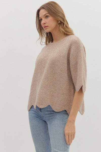 Woman wearing a beige sweater and blue jeans on a white background