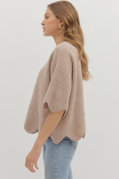 Woman wearing a beige sweater and light blue jeans on a white background