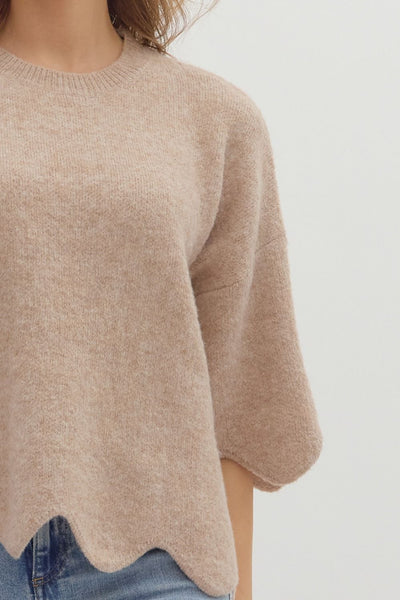 Beige sweater worn by a person on a white background