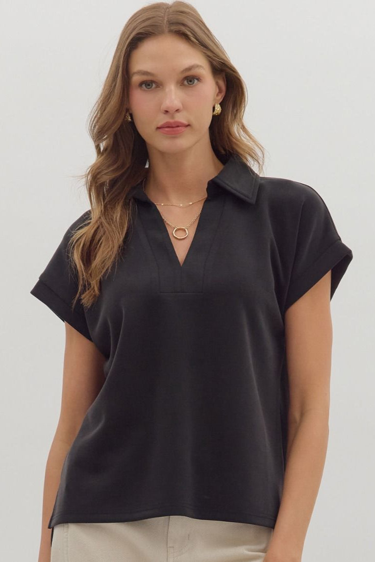 Woman wearing a black short-sleeve top and beige pants on a white background