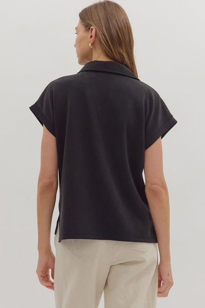 Woman wearing a black sleeveless top and beige pants on a white background