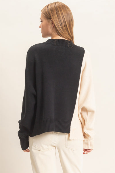 back of a model wearing black & cream sweater with white pants