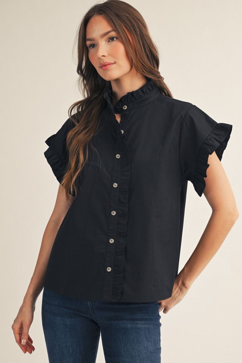 Woman wearing a black blouse with ruffled sleeves on a beige background