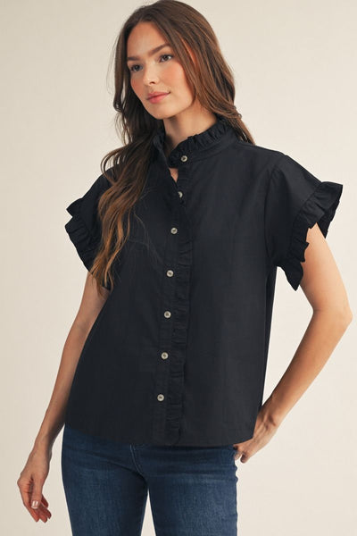 Woman wearing a black blouse with ruffled sleeves on a beige background