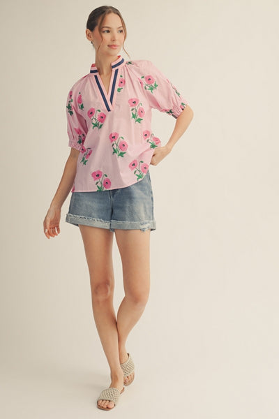 model wearing a pink floral top & cuffed denim shorts with a light background