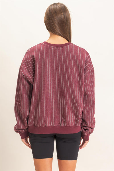 back of model wearing burgundy striped sweatshirt and black shorts with a light background
