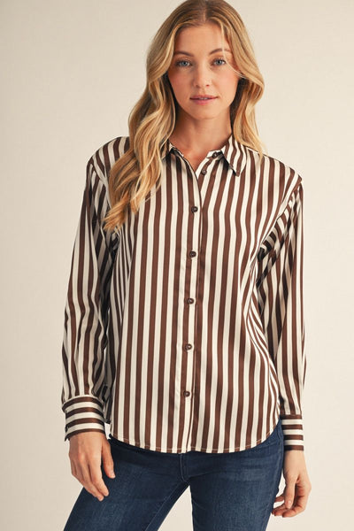 model wearing a brown striped top with jeans before a beige background