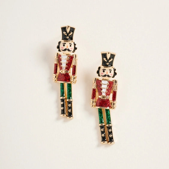 Nutcracker-themed earrings on a light beige background