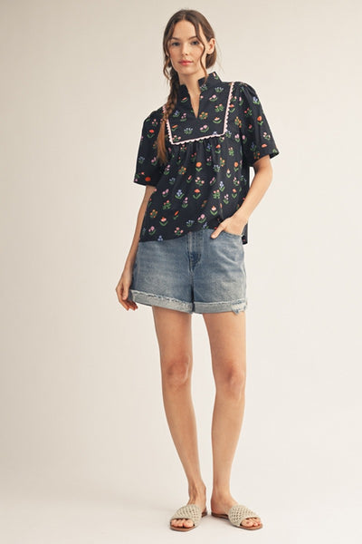 model wearing black floral top & cuffed denim shorts