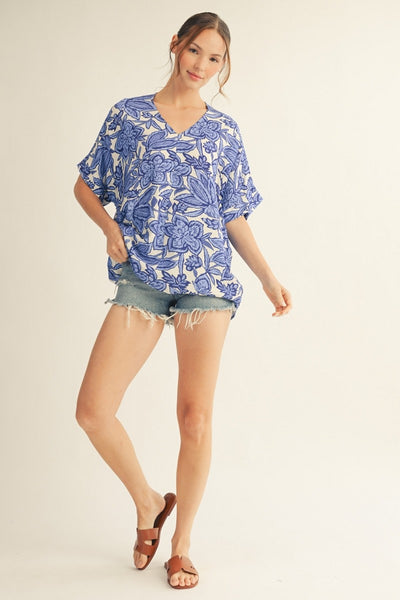 model wearing a blue & white floral top with cutoff denim shorts