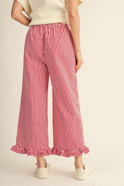 Person wearing red and white striped pants on a beige background
