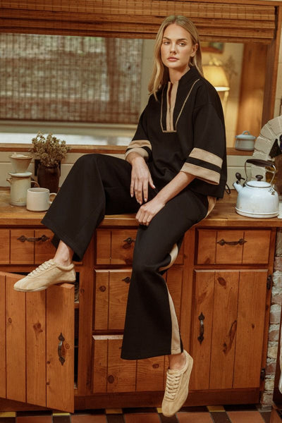 women wearing black and beige outfit sitting on rustic kitchen cabinet