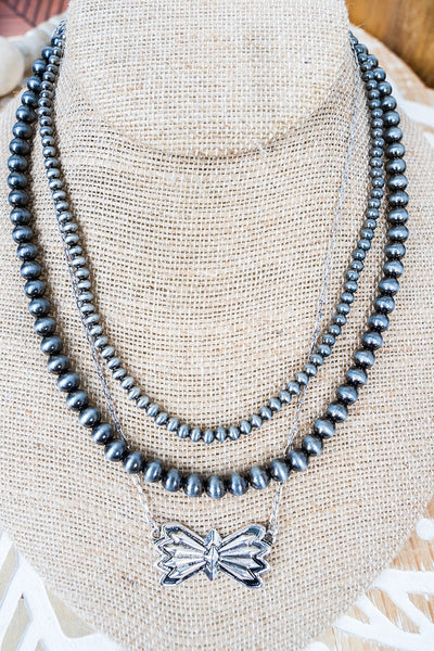 Triple strand necklace with bow pendant on bust display