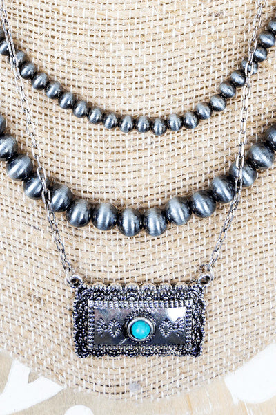 Triple strand necklace with close up of bar pendant on bust display.